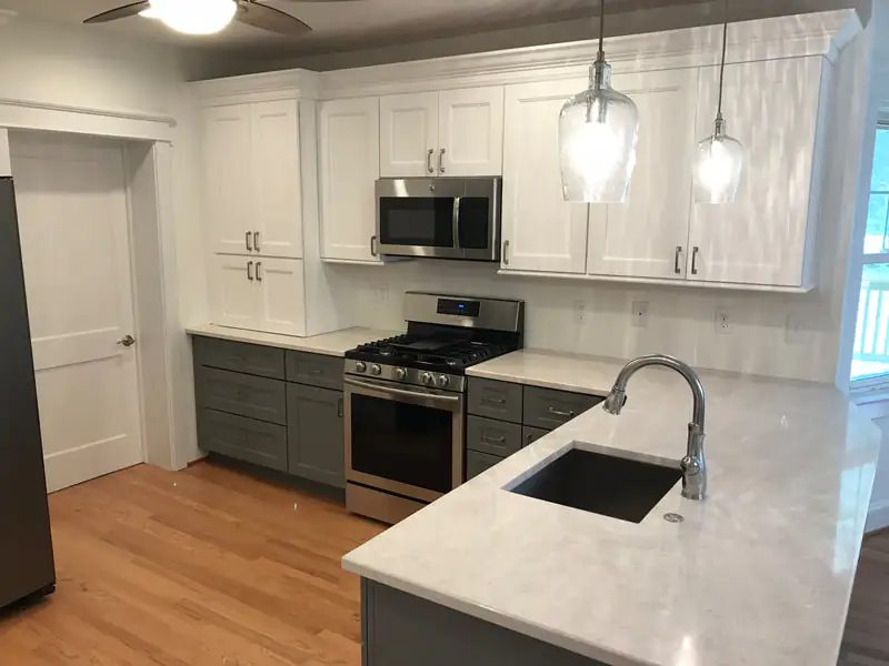 White upper and grey lower shaker kitchen with quartz peninsula