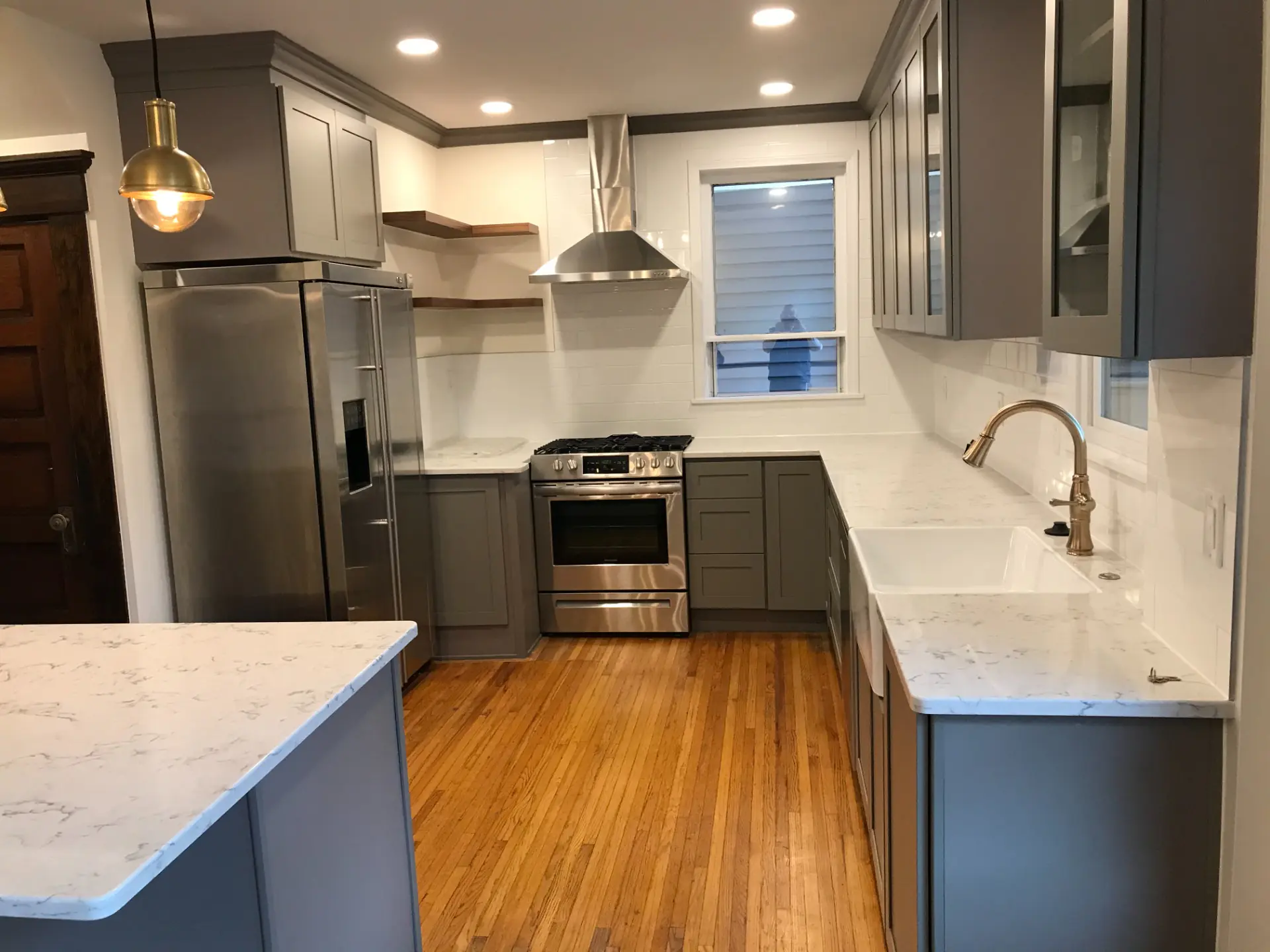 Grey shaker kitchen with brass pendant light and marble-look counters