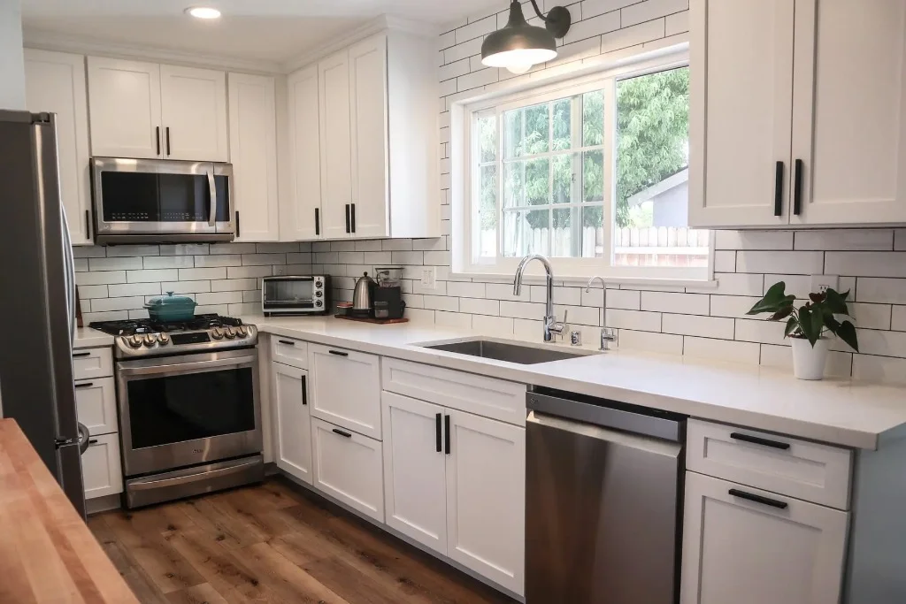 White shaker kitchen with black hardware and white subway tile backsplash