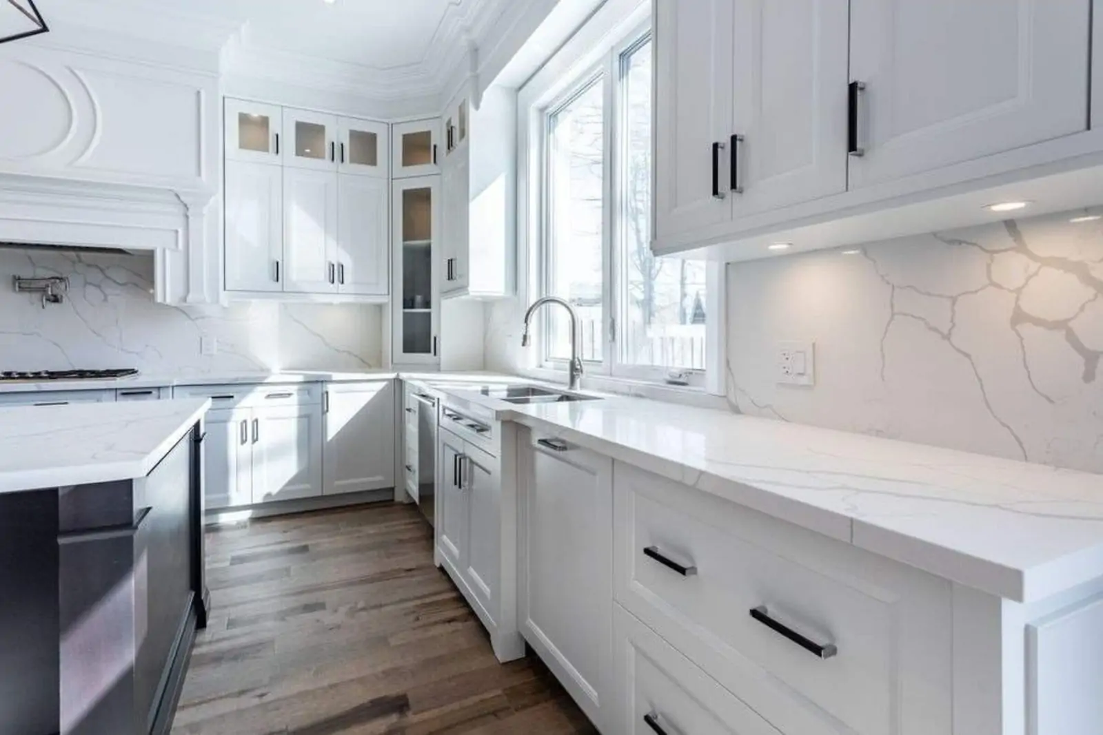 Traditional all-white kitchen with quartz counters and marble backsplash