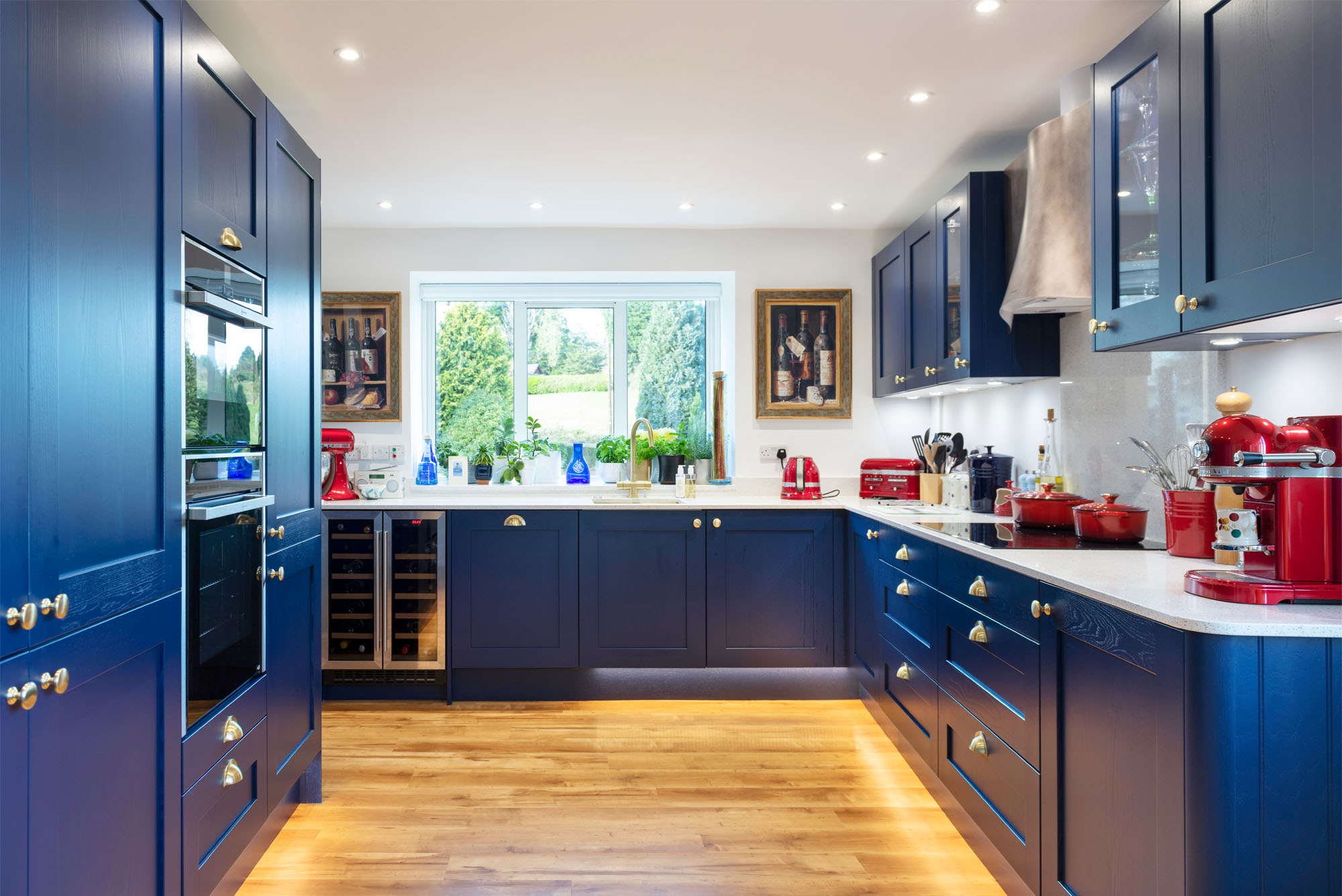 Bold navy blue shaker kitchen with brass knobs and quartz counters